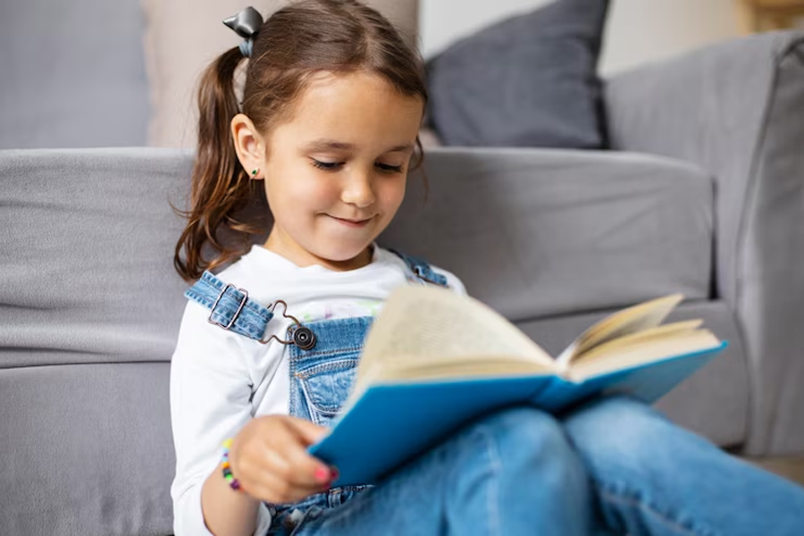 Девочка сидит на полу и читает книгу