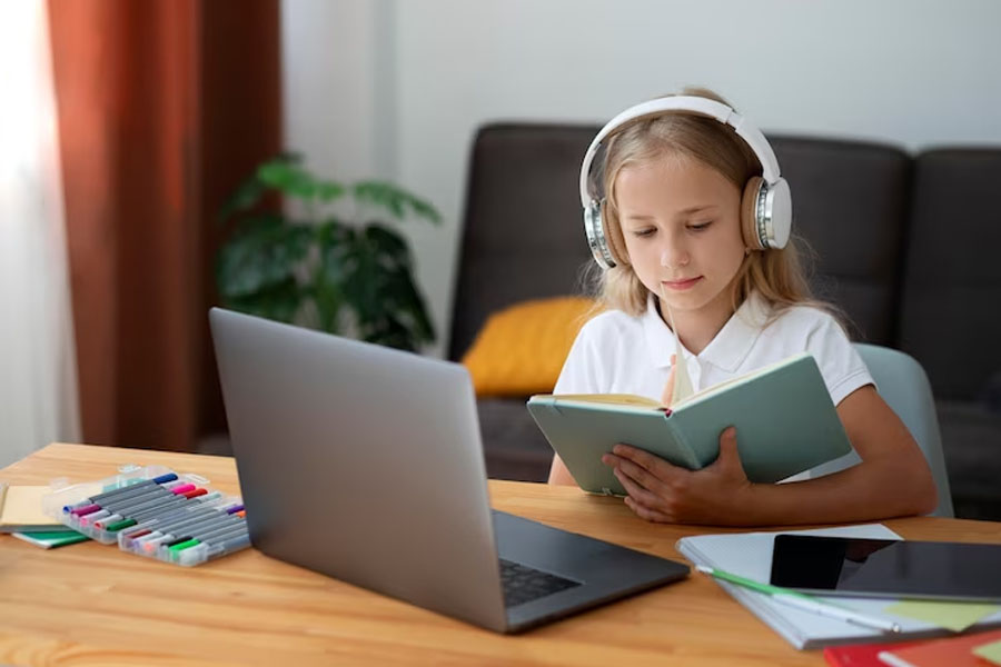 Девочка в наушниках смотрит в книгу