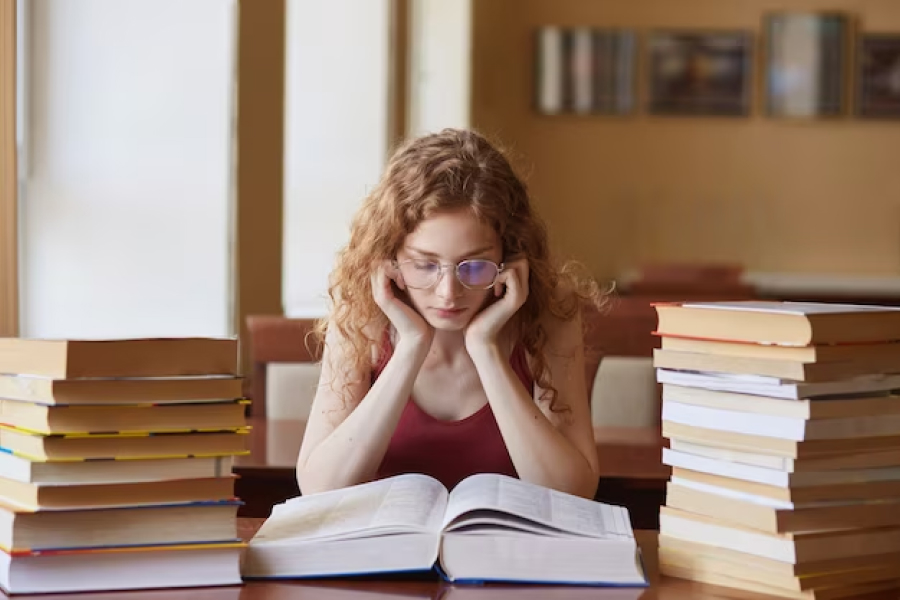 Девушка в библиотеке читает книги